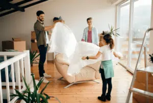Una famiglia felice che copre una poltrona con del pluriball in una stanza piena di scatoloni