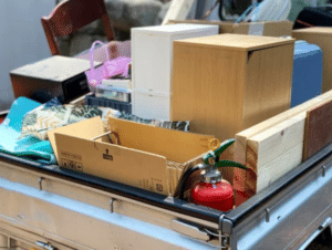 Diversi oggetti, tra cui un'estintore, piccoli mobiletti, una scatola, raccolti insieme in un carrello auto
