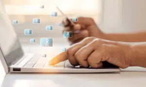 Primo piano sulla mano maschile mentre clicca un tasto sula tastiera d i un computer mentre controlla una tessera che tiene nella mano destra